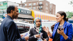 Alexandria Ocasio-Cortez, campaigning in New York City, talking to a man and a woman